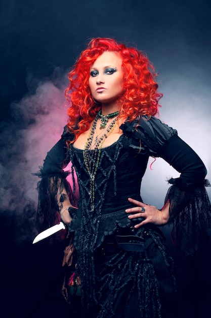 Halloween Witch crea magia. donna con i capelli rossi in costume da streghe