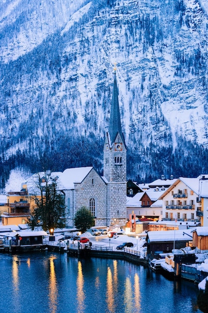 Hallstatt vicino a Salisburgo d'Austria, Europa. Inverno nel Salzkammergut. Viaggio verso la città austriaca con il lago in serata. Terra alpina con neve. Vista sul villaggio vicino alle montagne delle Alpi con la bella chiesa.