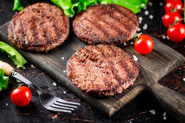 Hamburger alla griglia su un tagliere con pomodori e verdure