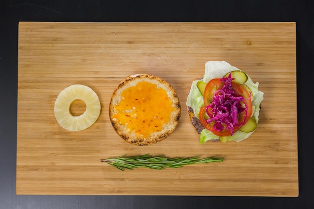 Hamburger aperto con ananas su tavola di legno, vista dall'alto