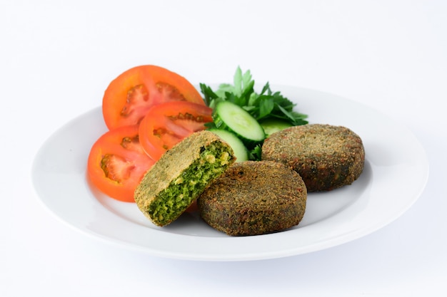 Hamburger arrostito della verdura con spinaci e piselli sul piatto bianco isolato su bianco