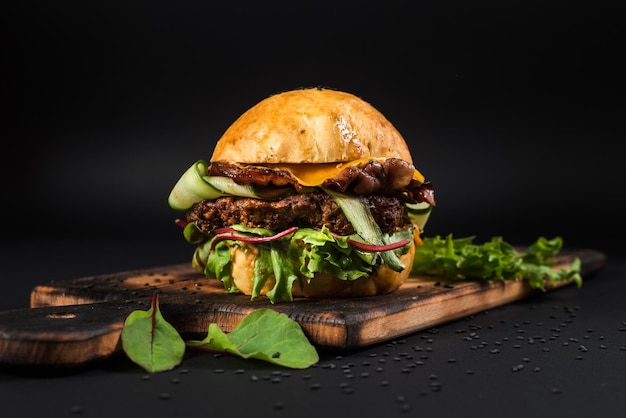 Hamburger artigianale gustoso con carne alla griglia, formaggio, pomodoro su fondo nero