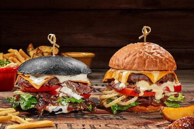 Hamburger bianchi e neri con tortino di vitello su tavola di legno con patate fritte