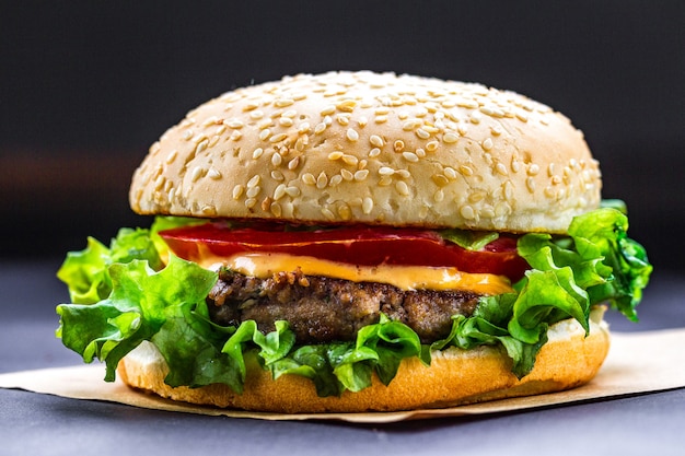 Hamburger casalingo fresco delizioso su un'oscurità. Cibo veloce e cattivo