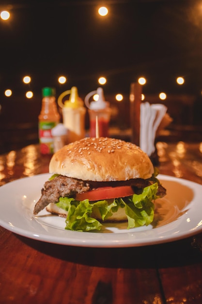 Hamburger classico con lattuga e pomodoro con le luci del food park sullo sfondo