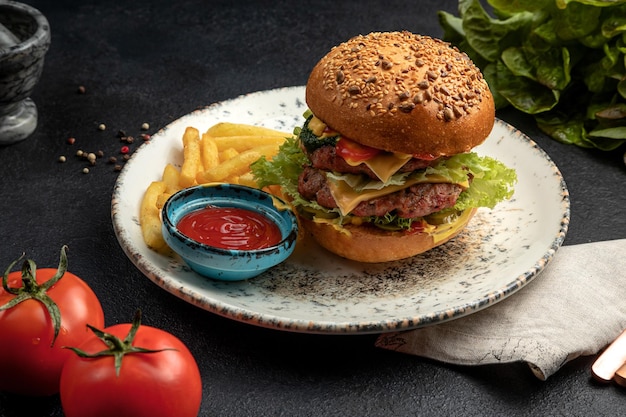 Hamburger con bistecca di verdure fritte e formaggio servito con patatine fritte e salsa su uno sfondo scuro