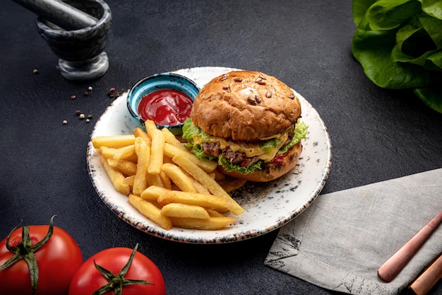 Hamburger con bistecca di verdure fritte e formaggio servito con patatine fritte e salsa su uno sfondo scuro