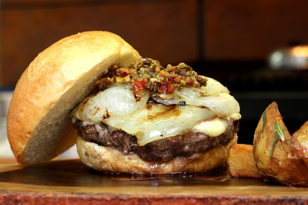 Hamburger con cipolla in cima e Chimichurri su uno sfondo di legno rustico