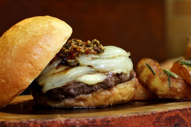 Hamburger con cipolla in cima e Chimichurri su uno sfondo di legno rustico