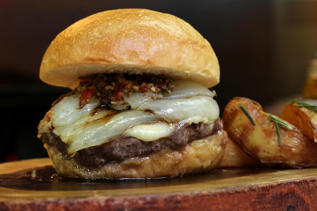 Hamburger con cipolla in cima e Chimichurri su uno sfondo di legno rustico