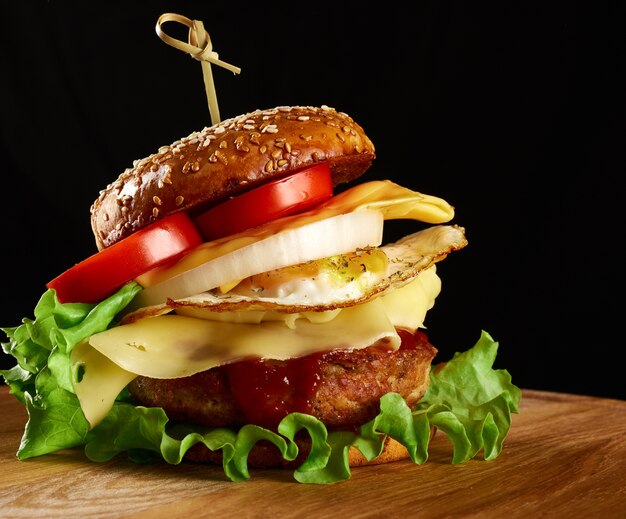 Hamburger con cotoletta di carne, formaggio, uovo fritto, pomodori, cetriolo