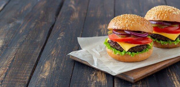 Hamburger con cotoletta, pomodoro, lattuga, cetriolo, cipolla e formaggio. Cucina americana. Fast food. Cheeseburger.