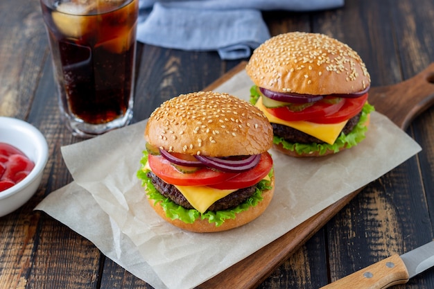 Hamburger con cotoletta, pomodoro, lattuga, cetriolo, cipolla e formaggio. Cucina americana. Fast food. Cheeseburger.