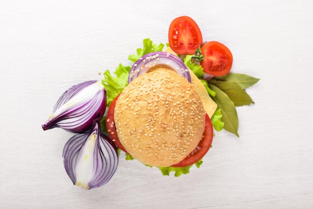 Hamburger con formaggio, carne, pomodori, cipolle ed erbe aromatiche su fondo in legno Vista dall'alto Spazio libero