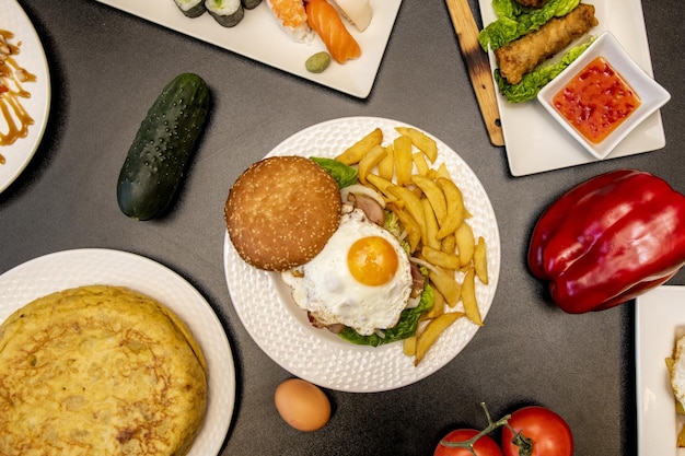 Hamburger con frittata di patate all'uovo fritte cetriolo e peperoni sul tavolo grigio