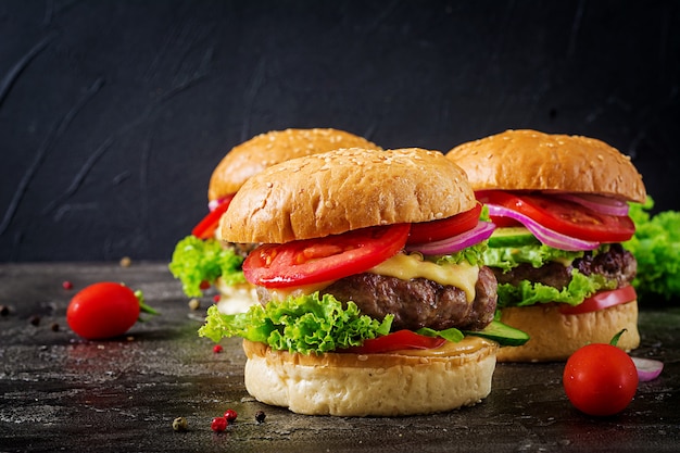 Hamburger con hamburger di carne di manzo e verdure fresche sulla superficie scura.