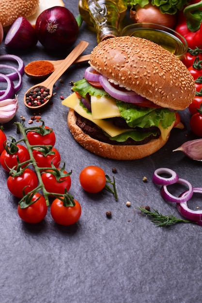 Hamburger con pomodori e altro cibo su superficie nera