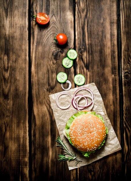 Hamburger cotto con verdure, formaggio e carne. Sullo sfondo di legno. Vista dall'alto.