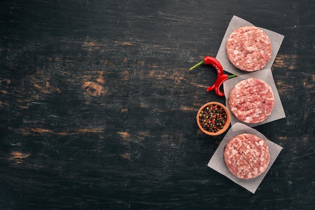 Hamburger crudo su fondo di legno nero Vista dall'alto Spazio libero per la copia