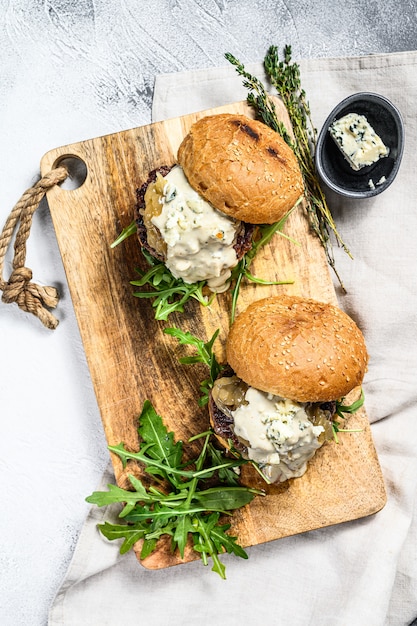 Hamburger deliziosi con gorgonzola, carne di manzo marmorizzata, marmellata di cipolle e rucola. Sfondo grigio. Vista dall'alto