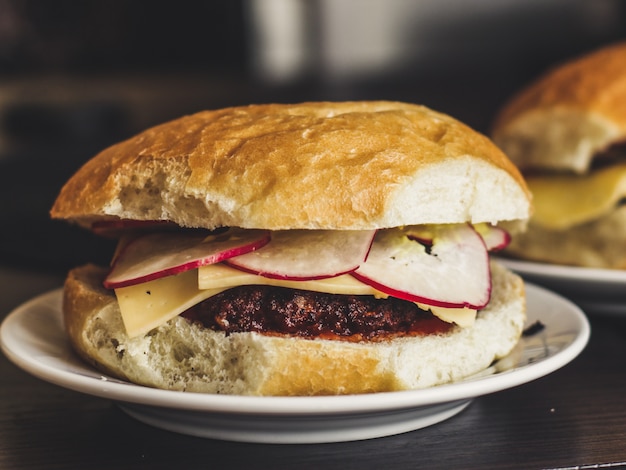 Hamburger delizioso con formaggio, ravanelli e salsa di pomodoro