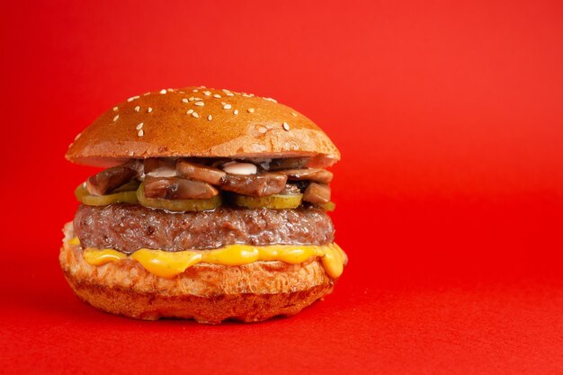 Hamburger delizioso su sfondo rosso. Hamburger malsani freschi saporiti con formaggio Fast food, concetto di cibo spazzatura.