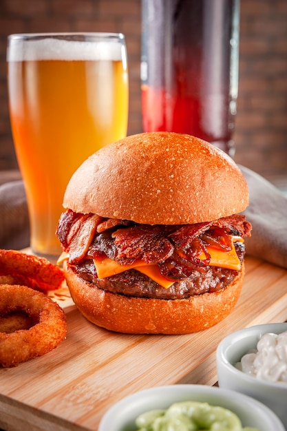 Hamburger di bacon delizioso con anelli di cipolla e birra.