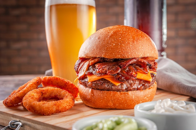 Hamburger di bacon delizioso con anelli di cipolla e birra.