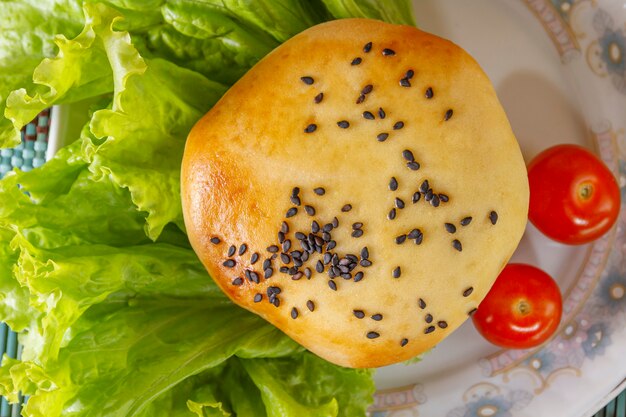 Hamburger di carne, gergilim, lattuga e pomodori su un piatto di porcellana