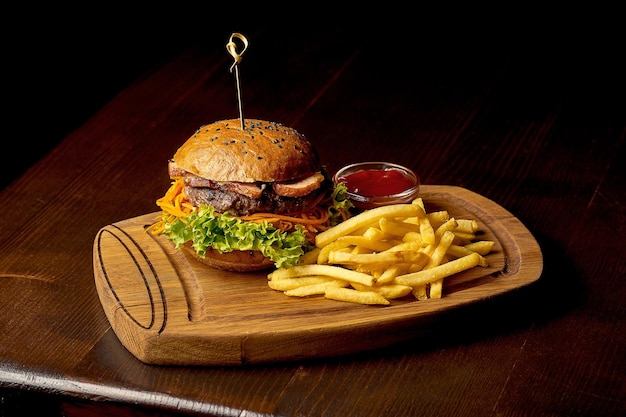 Hamburger di fast food americano con patatine fritte e salsa. Sfondo di legno scuro. Messa a fuoco selettiva.