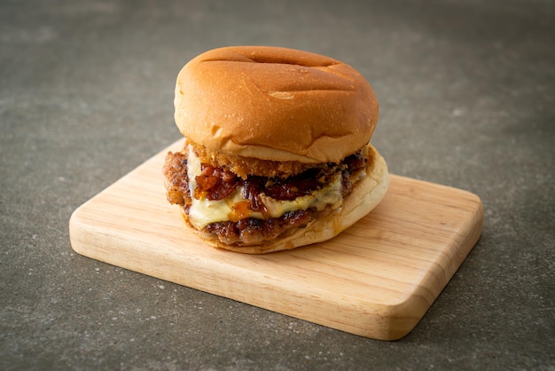 hamburger di maiale con formaggio, pancetta e anelli di cipolla su tavola di legno