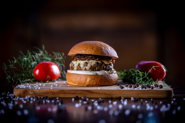 Hamburger di manzo artigianale con formaggio, cipolla caramellata e salsa su fondo di legno