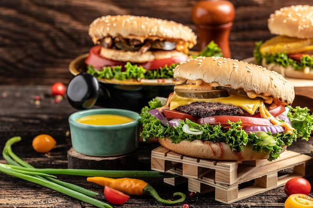 Hamburger di manzo artigianale con verdure su fondo di legno rustico. fast food e concetto di cibo spazzatura