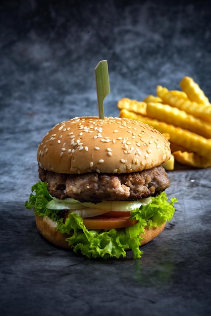 Hamburger di manzo artigianale e patatine fritte su sfondo nero