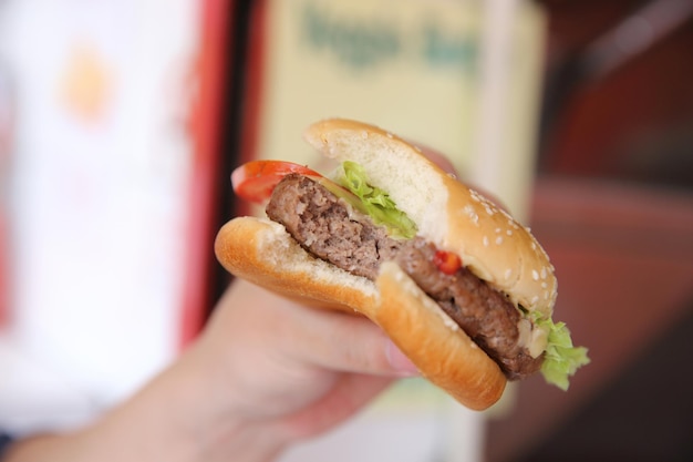 Hamburger di manzo che mangia su una mano dell'uomo in primo piano