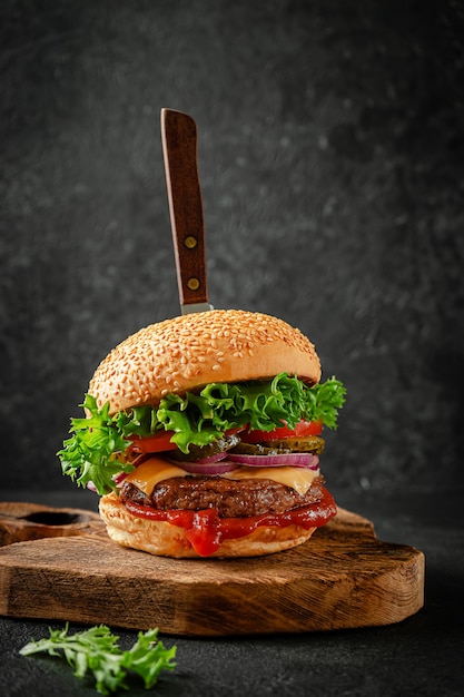 Hamburger di manzo con coltello sulla tavola di legno. Concetto di cibo di strada americano.