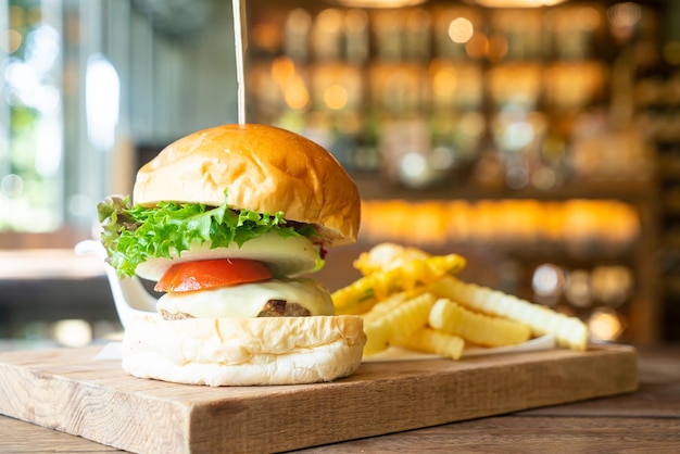 hamburger di manzo con formaggio e patatine su vassoio di legno