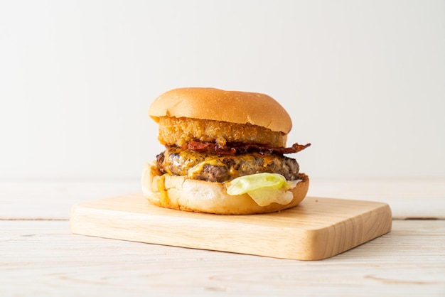 hamburger di manzo con formaggio, pancetta e anelli di cipolla su tavola di legno