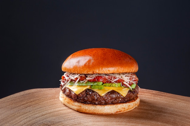 Hamburger di manzo delizioso con salsa di pomodoro, parmigiano e lattuga su un tavolo di legno su sfondo scuro. Copia spazio