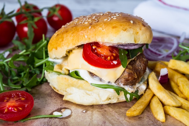 Hamburger di manzo fatto in casa con formaggio e patate fritte su fondo di legno