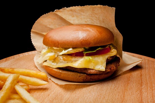 Hamburger di manzo fatto in casa su uno sfondo di legno Hamburger fresco e gustoso con patatine fritte su tavola di legno