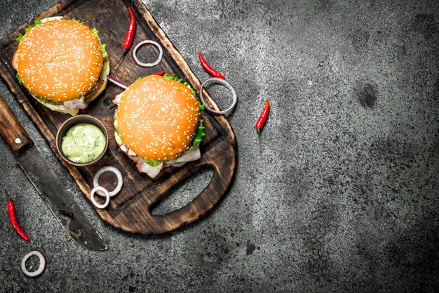 Hamburger di manzo fresco con un coltello sulla tavola su uno sfondo rustico