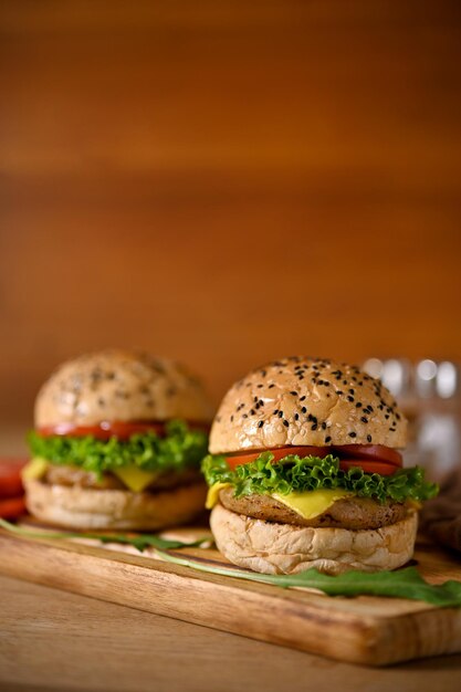 Hamburger di manzo gustosi e succosi su vassoio di legno Hamburger di manzo con diapositive di pomodoro lattuga al formaggio