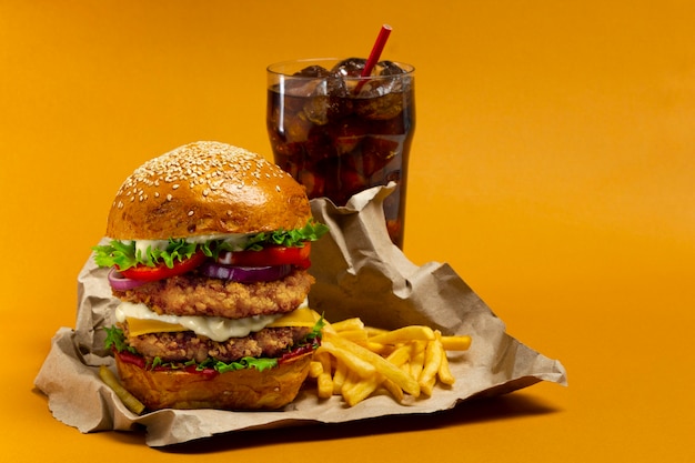 Hamburger di pollo con cola e patate fritte su sfondo arancione