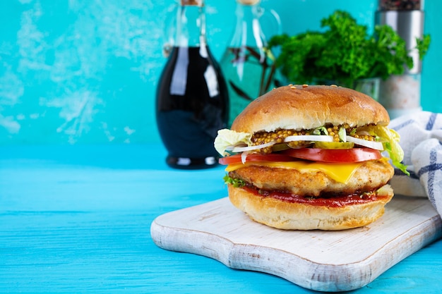 Hamburger di pollo gustoso con lattuga, formaggio, pomodoro e sottaceti Panino fast food con cotoletta di pollo