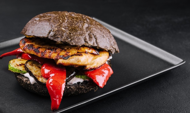 Hamburger di pollo gustoso fresco su un vassoio nero