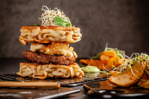 Hamburger di spaghetti di riso cinese ramen, cotoletta e insalata di pollo e maiale