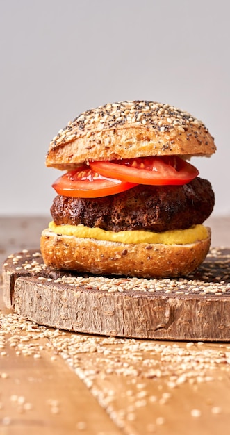 Hamburger fatti in casa con pomodori e senape sul tavolo di legno.