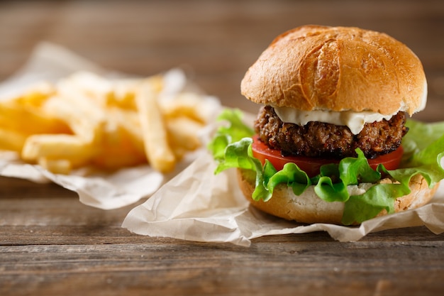 Hamburger fatti in casa e patatine fritte su un piatto di legno