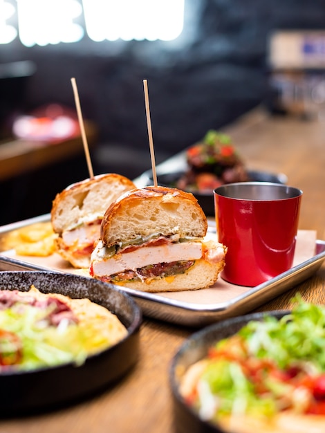 Hamburger fatto in casa alla griglia gustoso delizioso con carne di manzo, formaggio, pancetta e salsa su un tavolo di legno con spazio per copia. Mani che tengono hamburger con patatine fritte e birra. Gruppo di amici che mangiano fast food